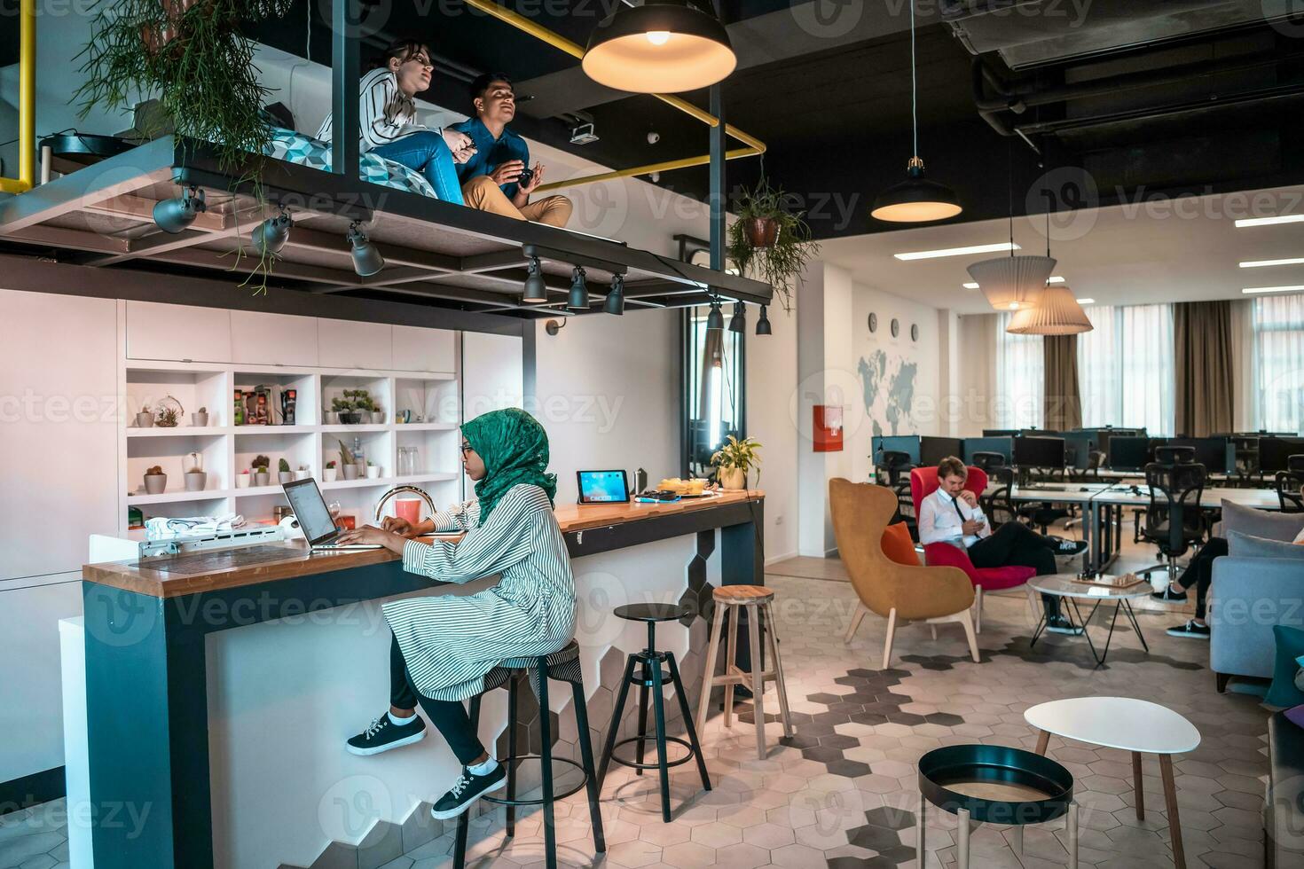 Group of casual multiethnic business people taking break from the work doing different things while enjoying free time in relaxation area at modern open plan startup office photo