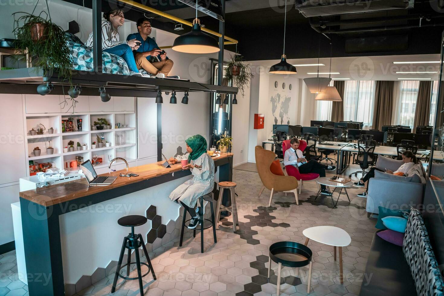 Group of casual multiethnic business people taking break from the work doing different things while enjoying free time in relaxation area at modern open plan startup office photo