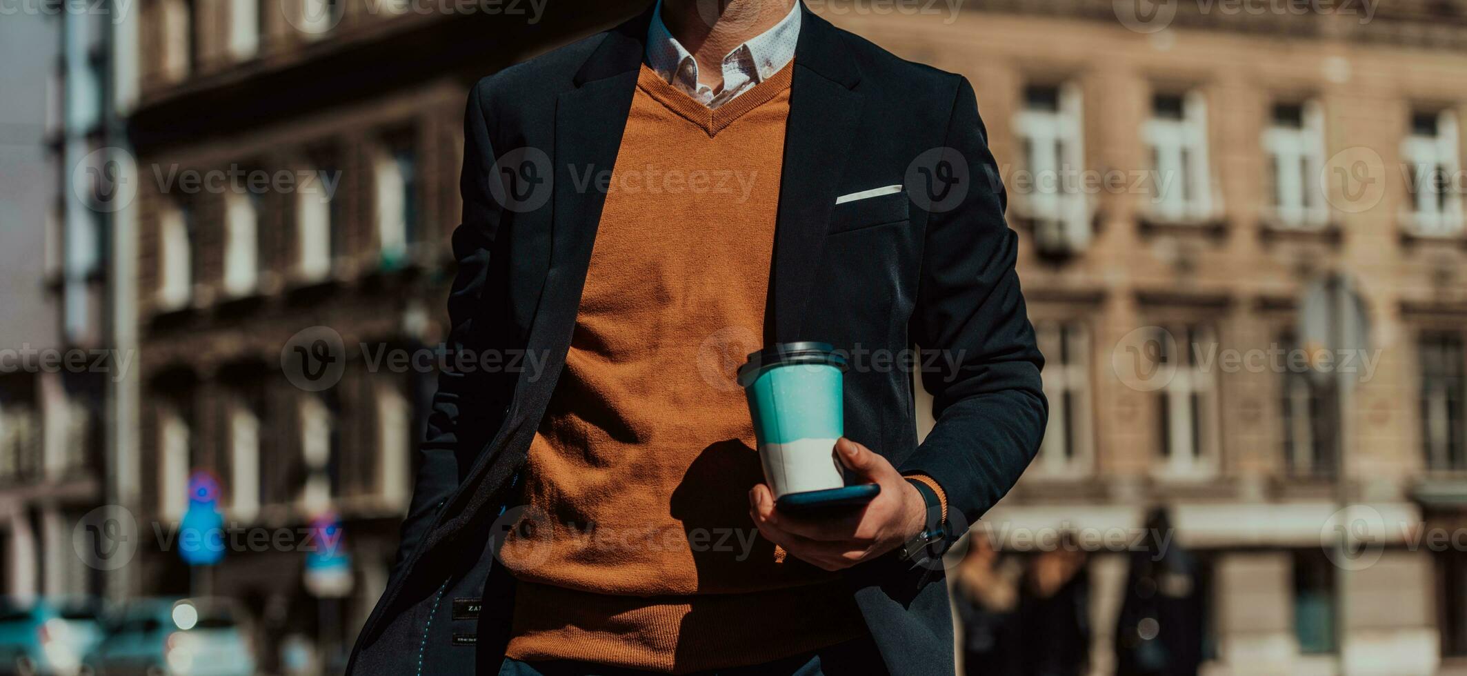 Going to airport terminal. Confident businessman traveler walking on city streets and pulling his suitcase drinking coffee and speaking on smartphone photo