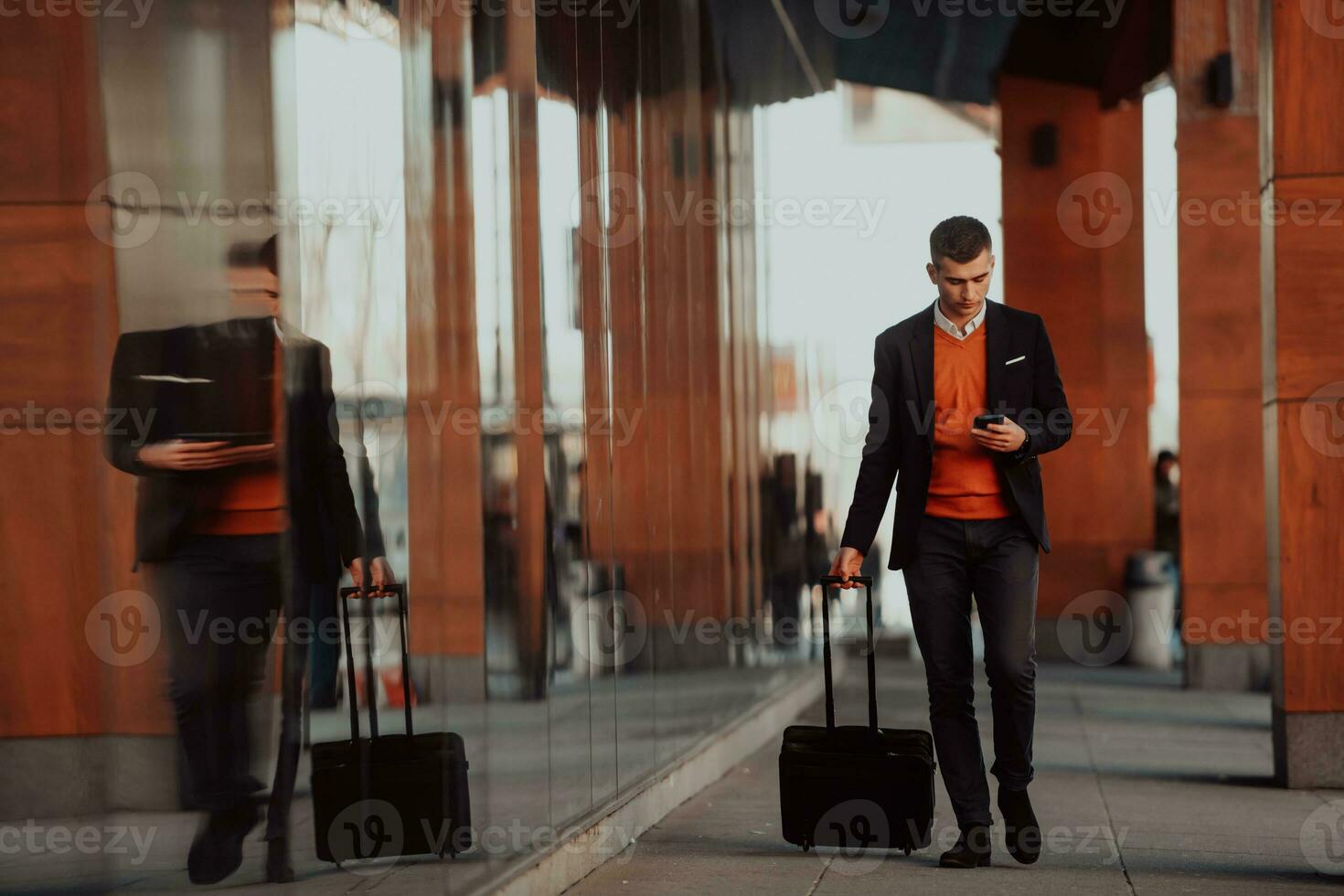 Going to airport terminal. Confident businessman traveler walking on city streets and pulling his suitcase drinking coffee and speaking on smartphone photo