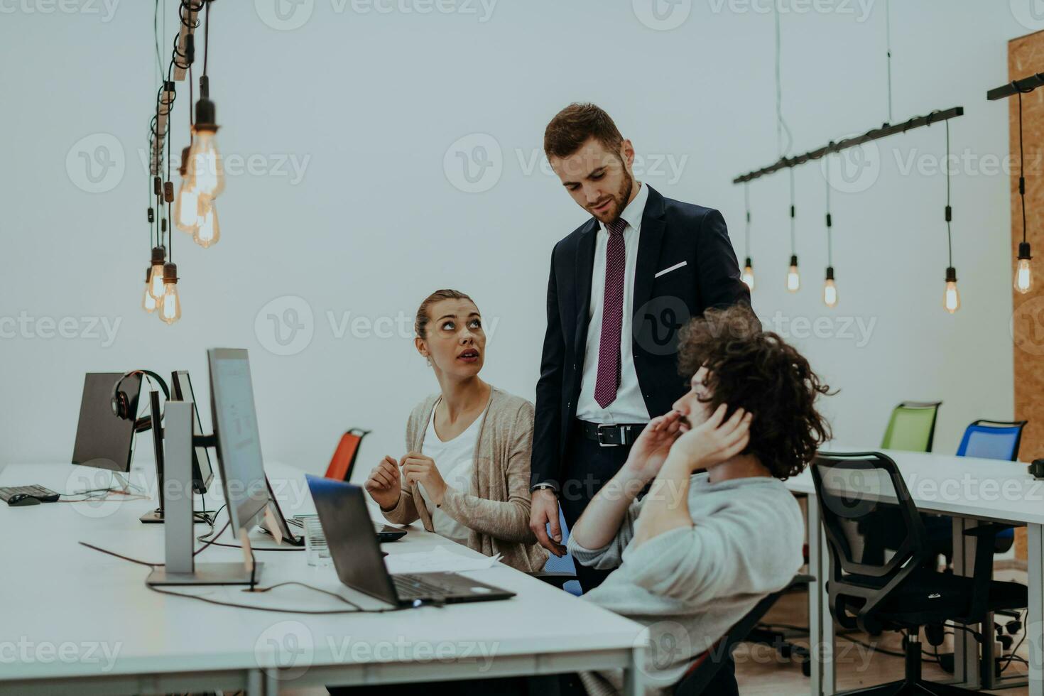 Group of multi-ethnic colleagues working on desktop computers, laptop and sharing their ideas in a modern office space.Young influencers work on online marketing projects. photo