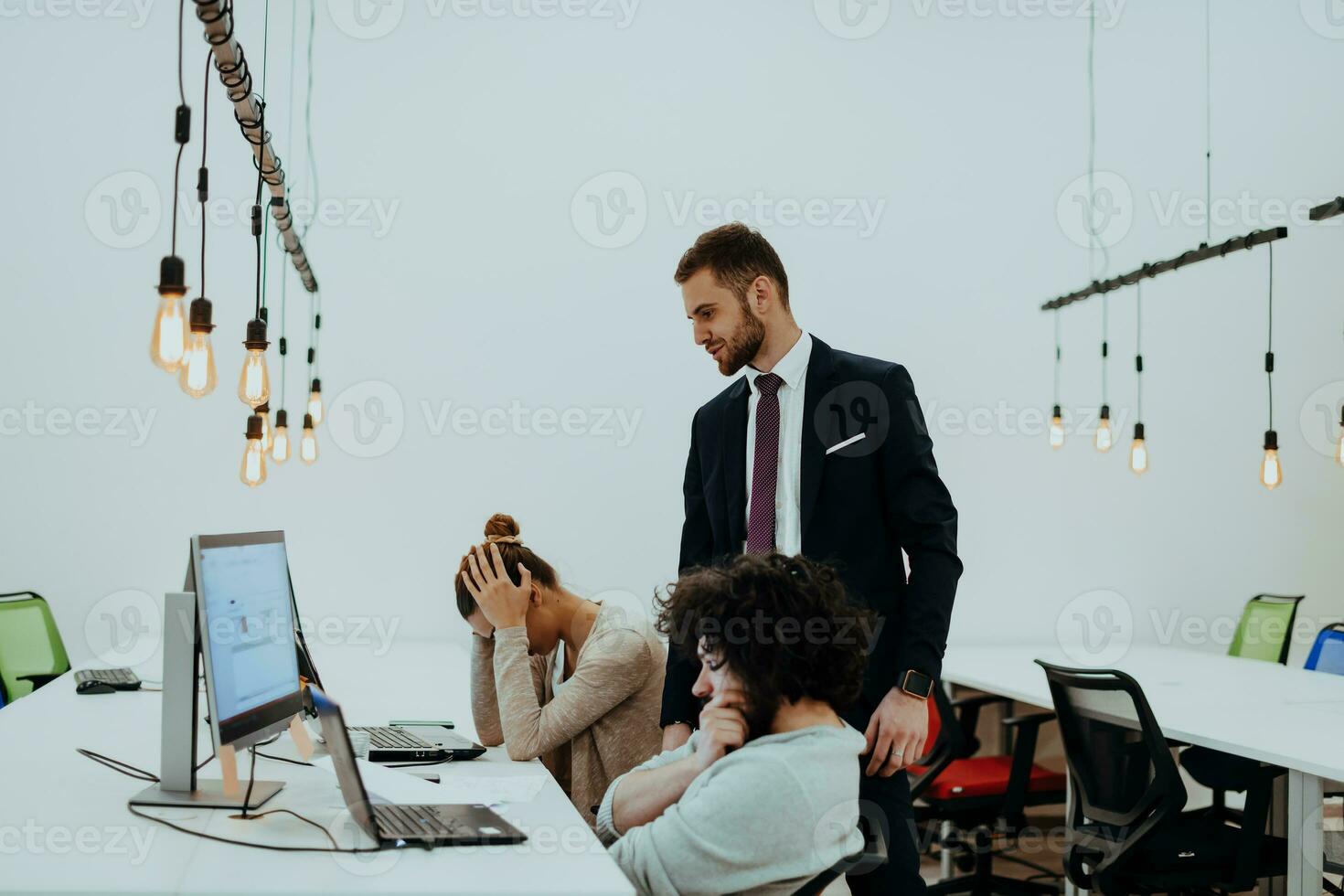 Group of multi-ethnic colleagues working on desktop computers, laptop and sharing their ideas in a modern office space.Young influencers work on online marketing projects. photo