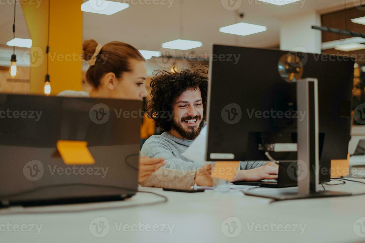 Two colleagues working on a project in modern startup offices. Guy with afro haircut and a female blonde employee working at the office. photo