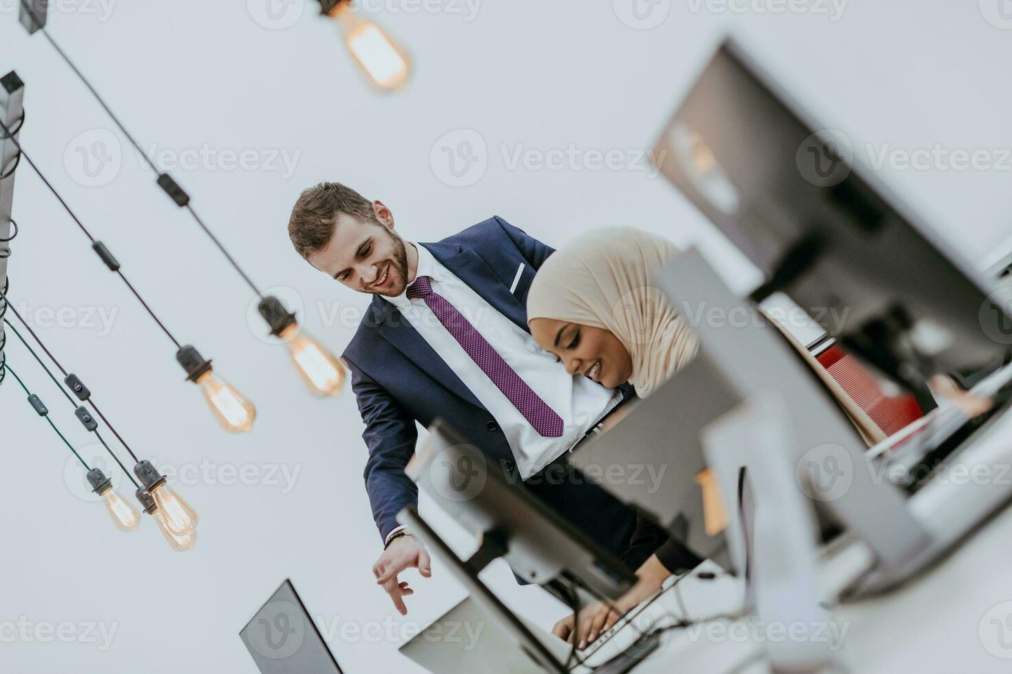 Group of multi-ethnic colleagues working on desktop computers, laptop and sharing their ideas in a modern office space.Young influencers work on online marketing projects. photo