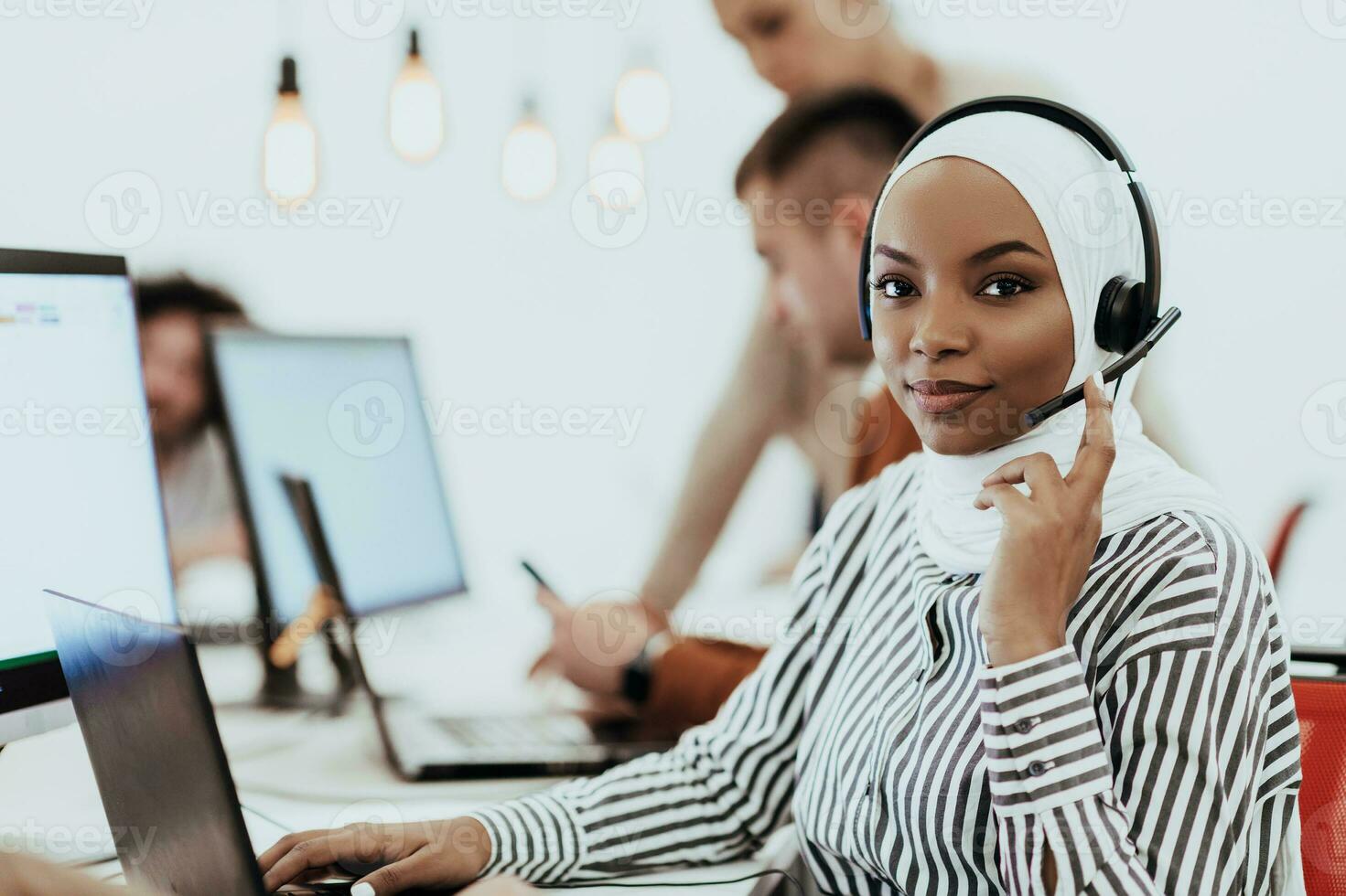 African American muslim woman with hijab and headset working as customer support in a modern office. photo