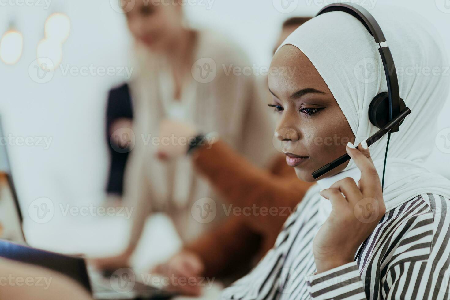 African American muslim woman with hijab and headset working as customer support in a modern office. photo