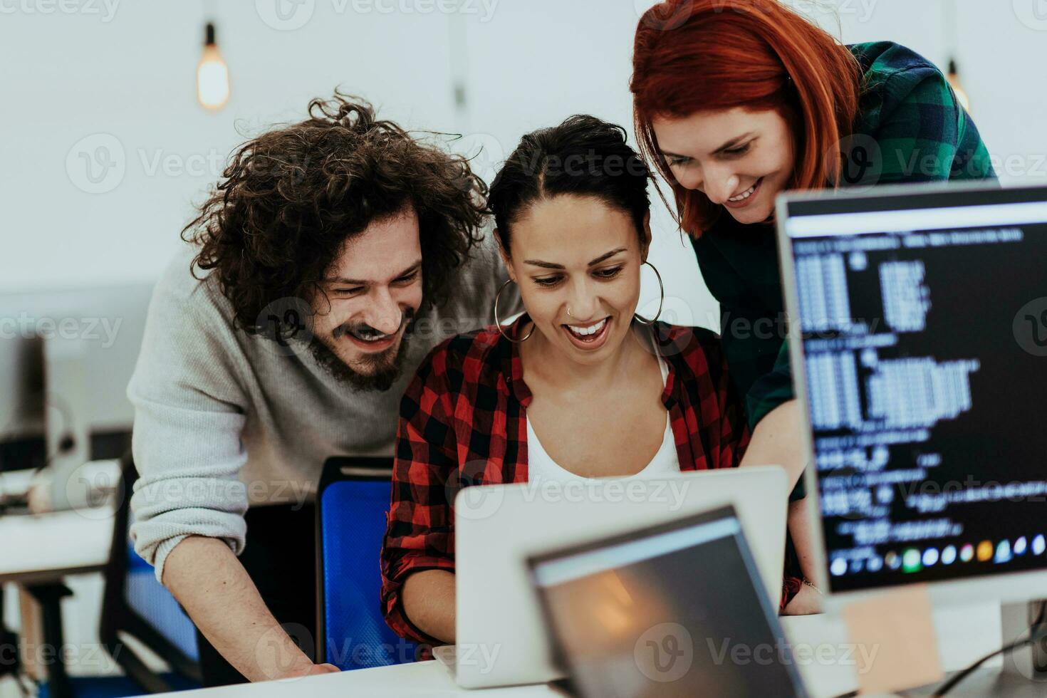 Group of multi-ethnic colleagues working on desktop computers, laptop and sharing their ideas in a modern office space.Young influencers work on online marketing projects. photo