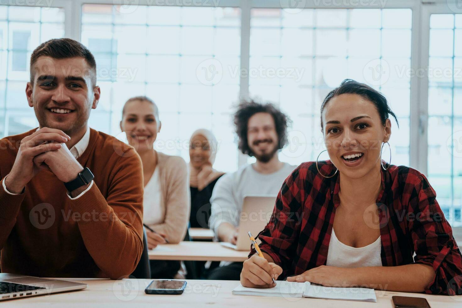 A group of diverse young men and women sit in a modern classroom and listen to a lecture on business training photo
