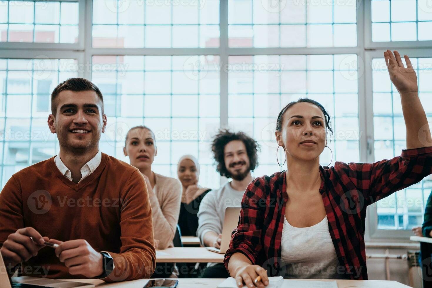 A group of diverse young men and women sit in a modern classroom and listen to a lecture on business training photo