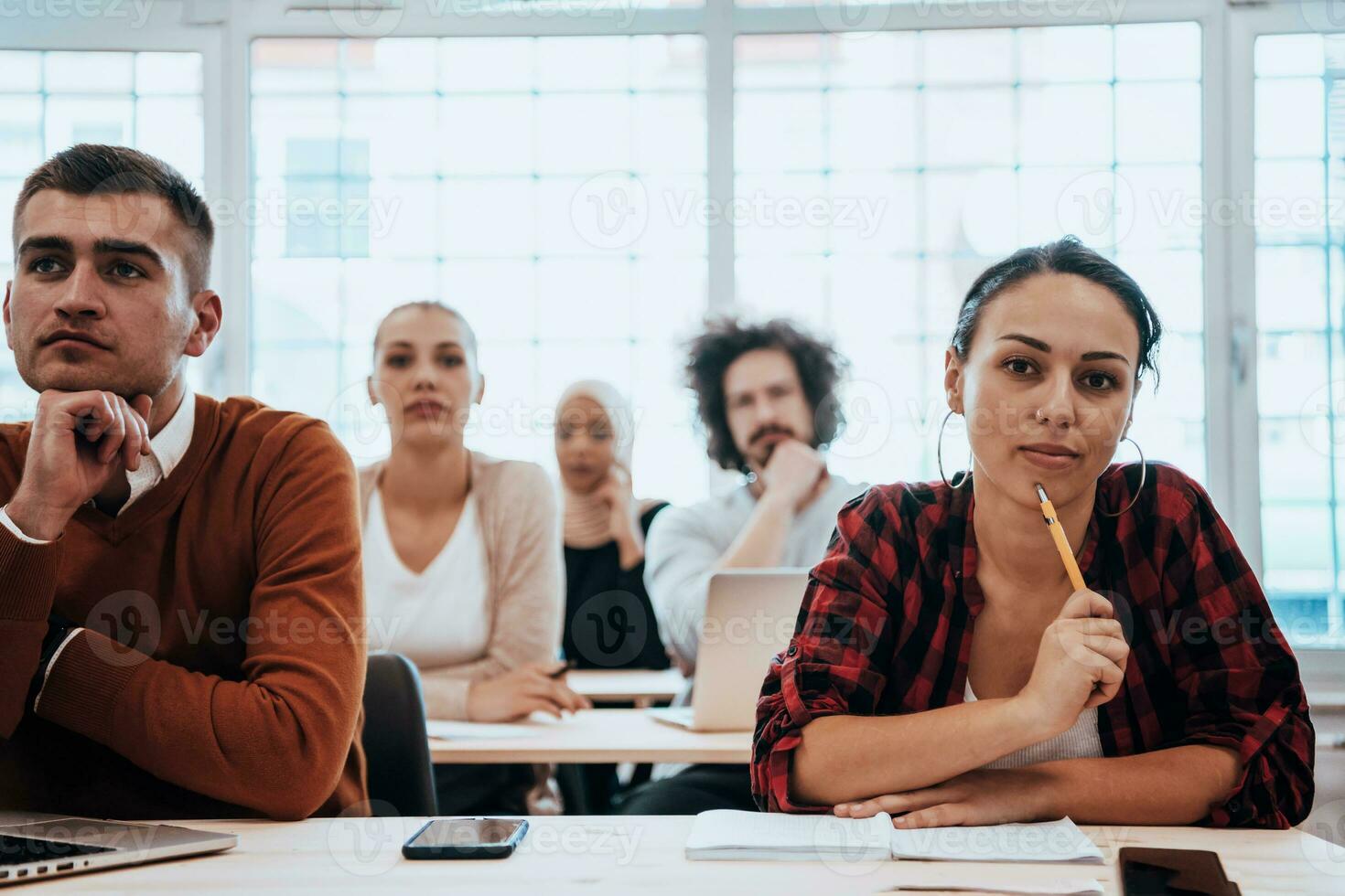 A group of diverse young men and women sit in a modern classroom and listen to a lecture on business training photo