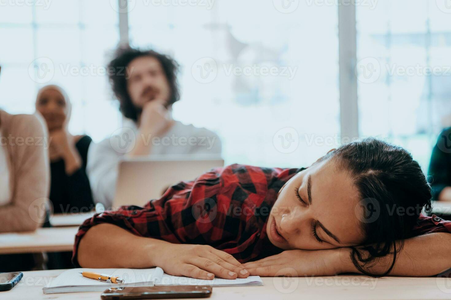 Tired woman napping on the table during a lecture in the classroom photo