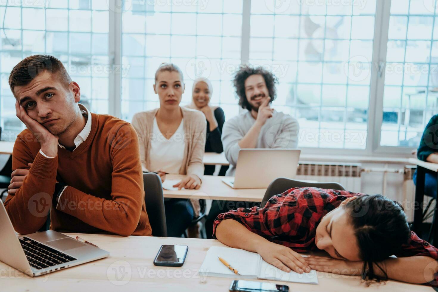 Tired woman napping on the table during a lecture in the classroom photo