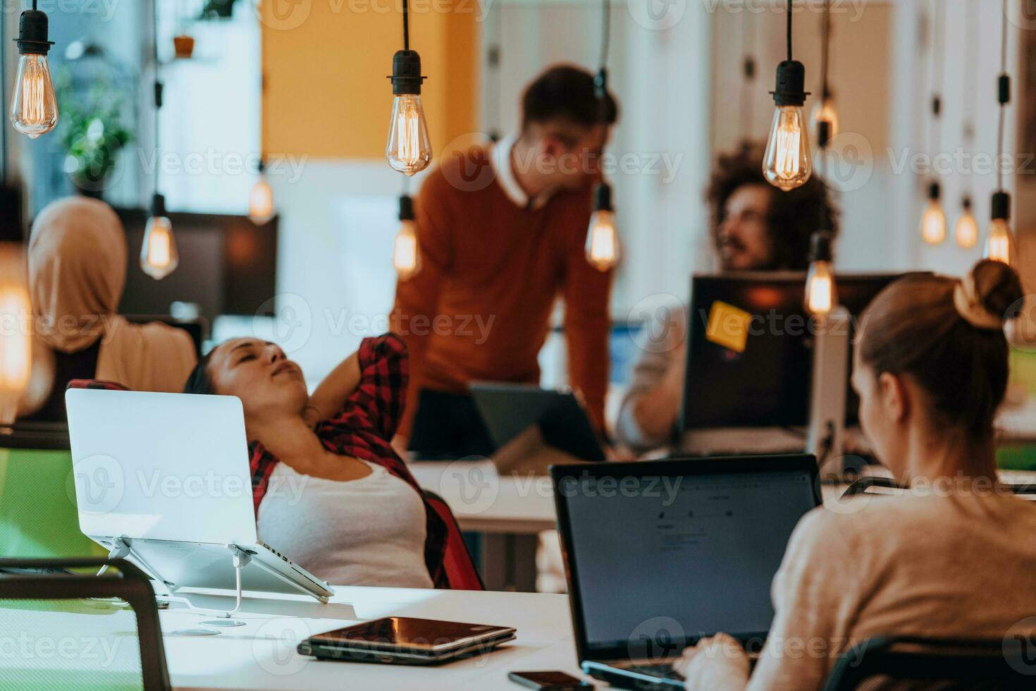 Group of multi-ethnic colleagues working on desktop computers, laptop and sharing their ideas in a modern office space.Young influencers work on online marketing projects. photo