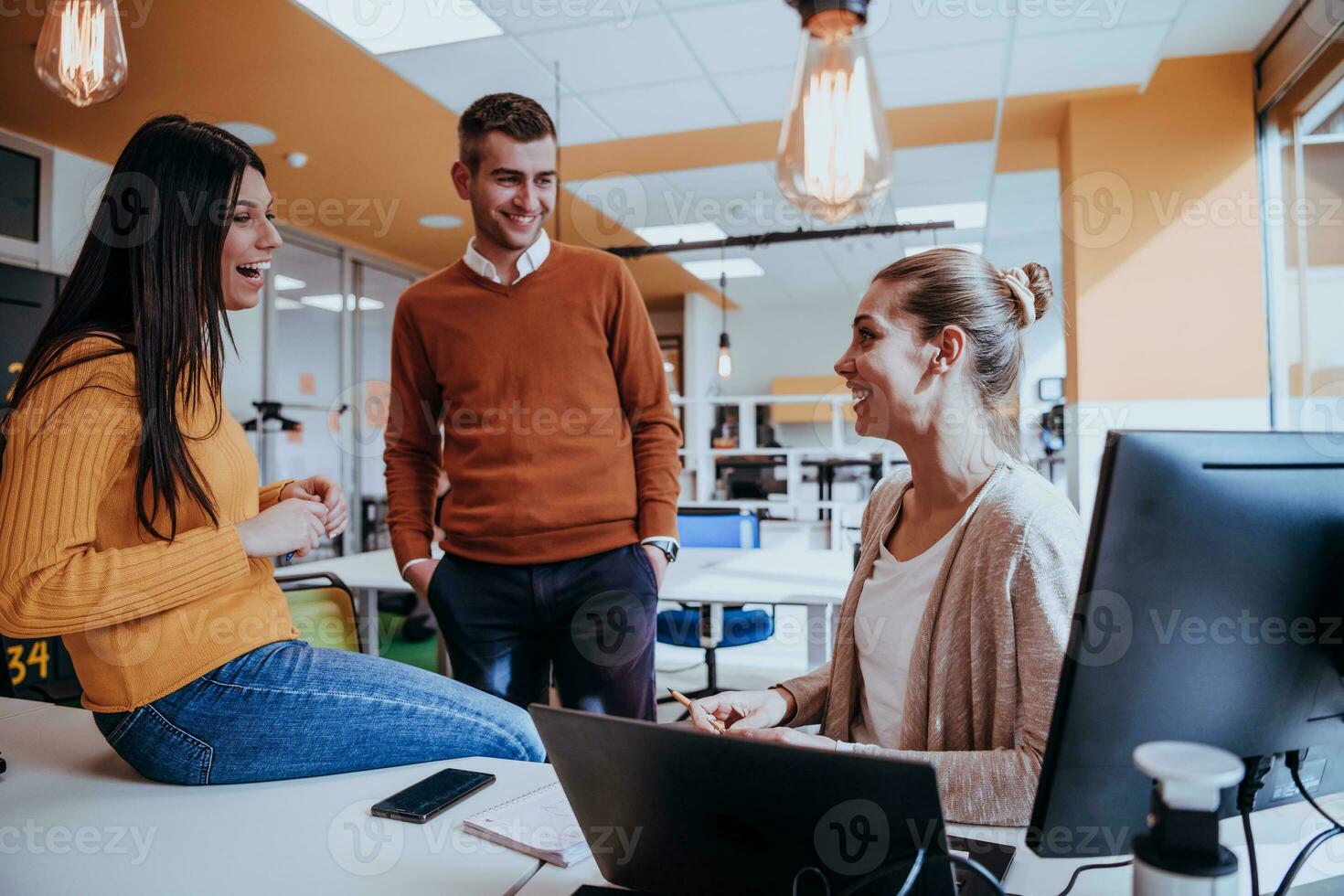 Group of multi-ethnic colleagues working on desktop computers, laptop and sharing their ideas in a modern office space.Young influencers work on online marketing projects. photo