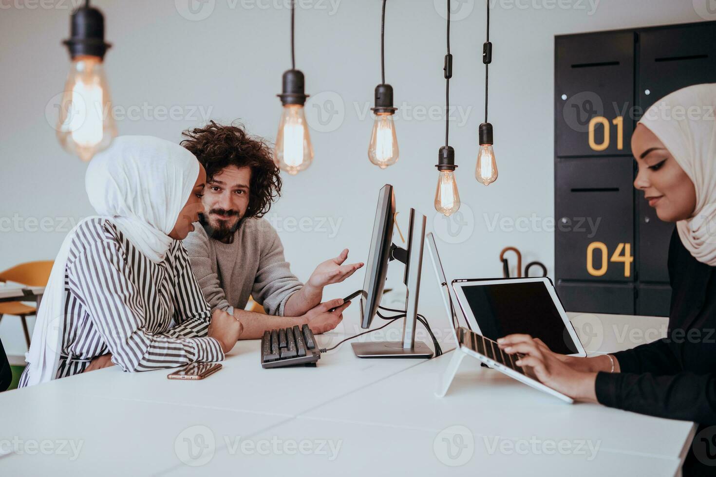 Group of multi-ethnic colleagues working on desktop computers, laptop and sharing their ideas in a modern office space.Young influencers work on online marketing projects. photo