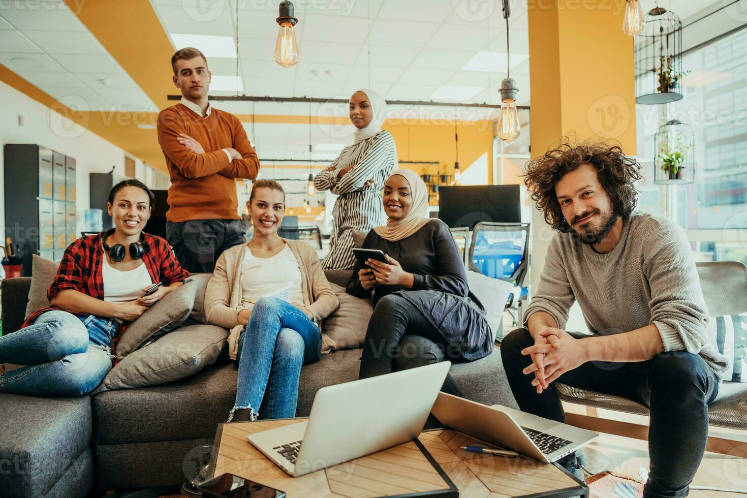 Group of multi-ethnic colleagues working on desktop computers, laptop and sharing their ideas in a modern office space.Young influencers work on online marketing projects. photo