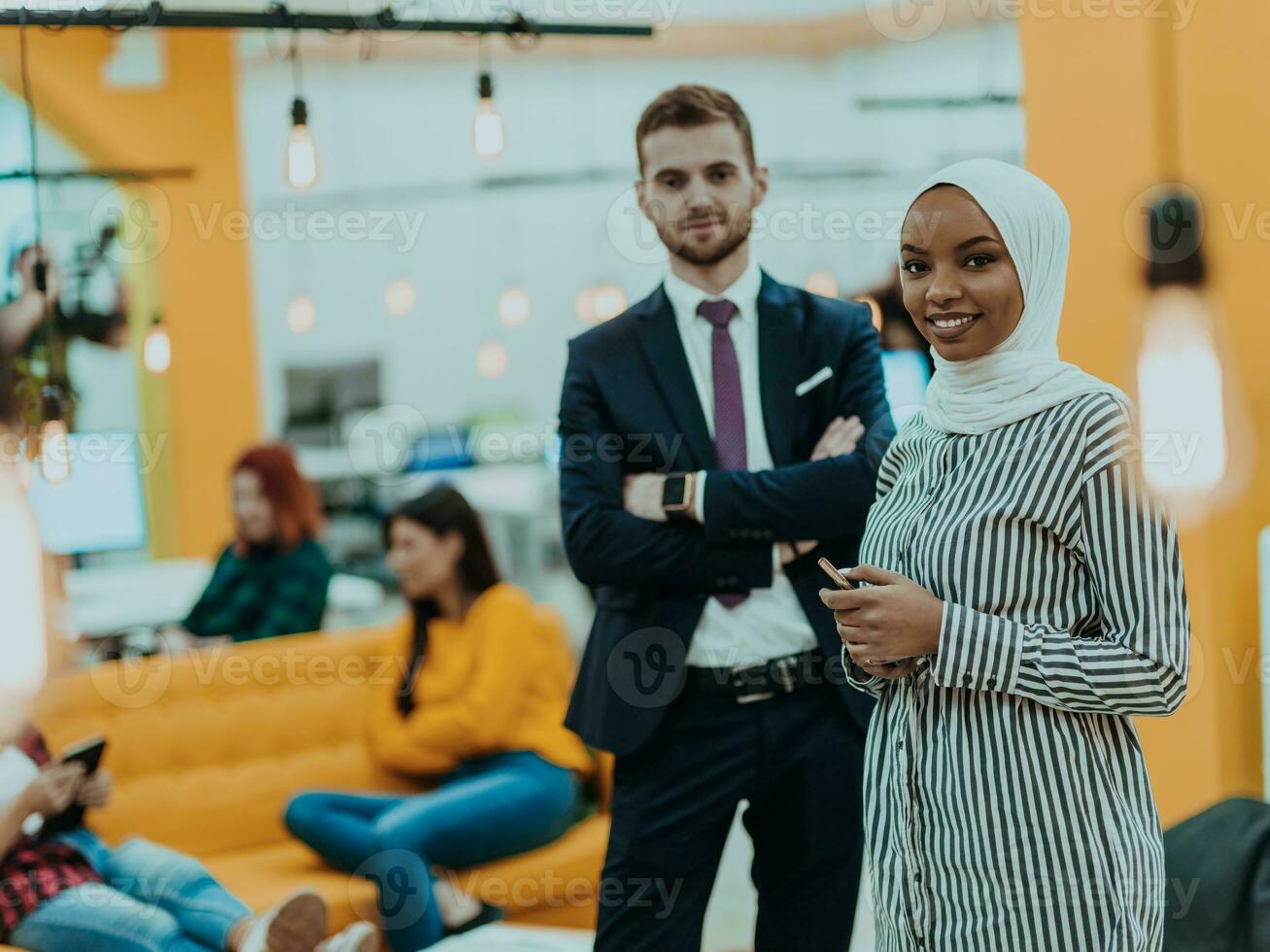 Portrait of a formal businessman and young African American businesswoman posing with their team in a modern startup office. Marketing concept. Multi-ethnic society. photo