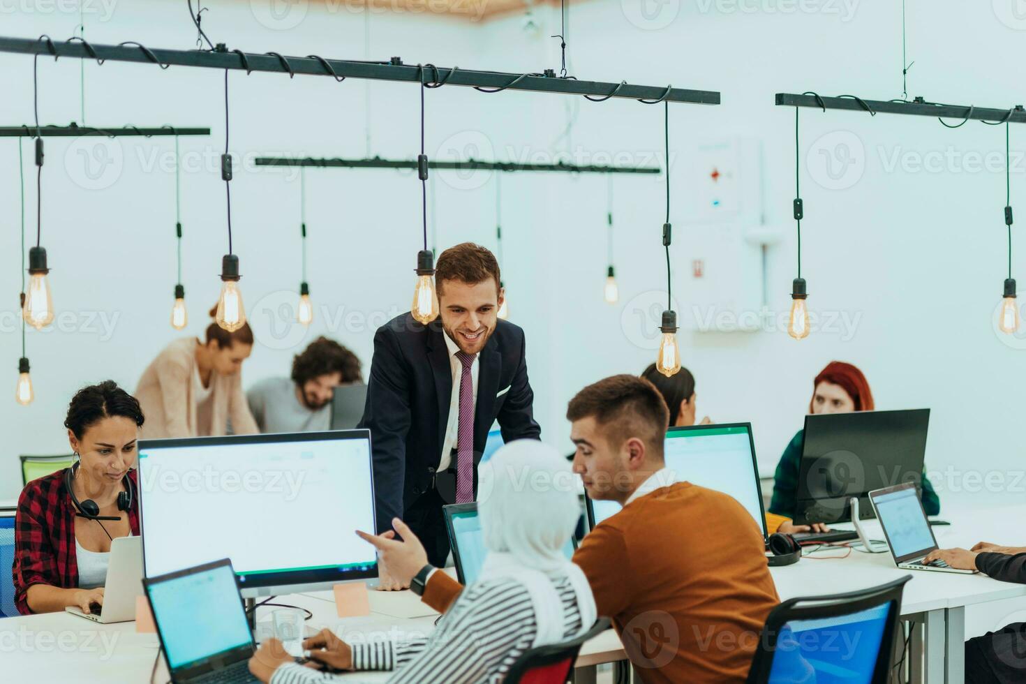 Group of multi-ethnic colleagues working on desktop computers, laptop and sharing their ideas in a modern office space.Young influencers work on online marketing projects. photo