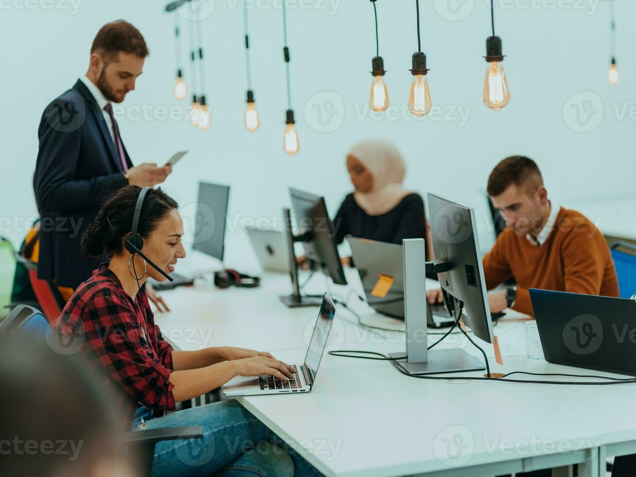 Group of multi-ethnic colleagues working on desktop computers, laptop and sharing their ideas in a modern office space.Young influencers work on online marketing projects. photo