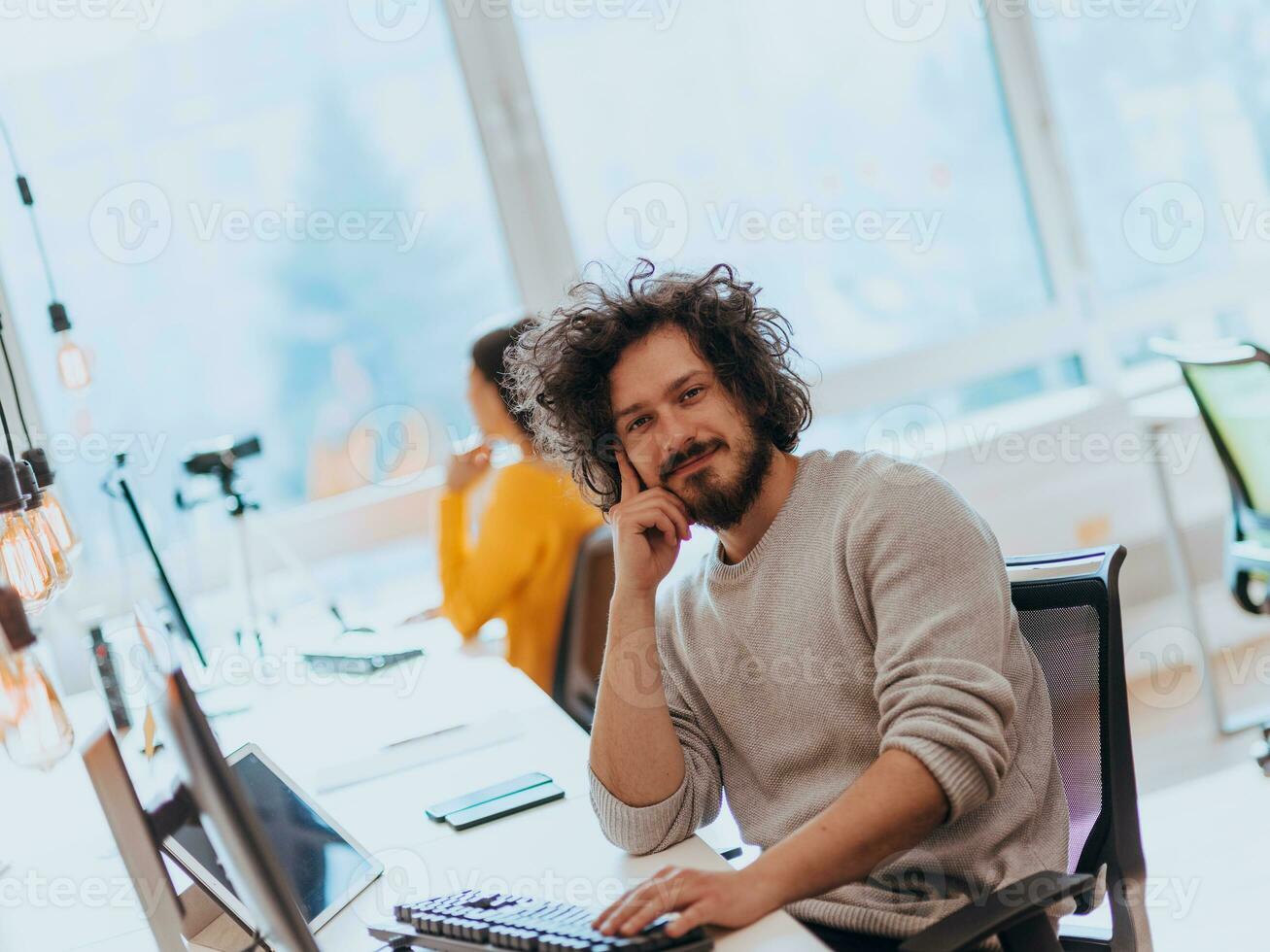Two men discuss a project while looking at a computer monitor in a modern office photo