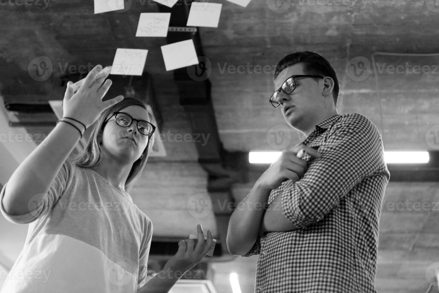young couple at modern office interior writing notes on stickers photo
