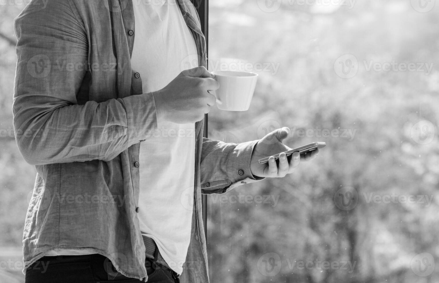 Clouseup of young man using mobile and drinking coffe photo