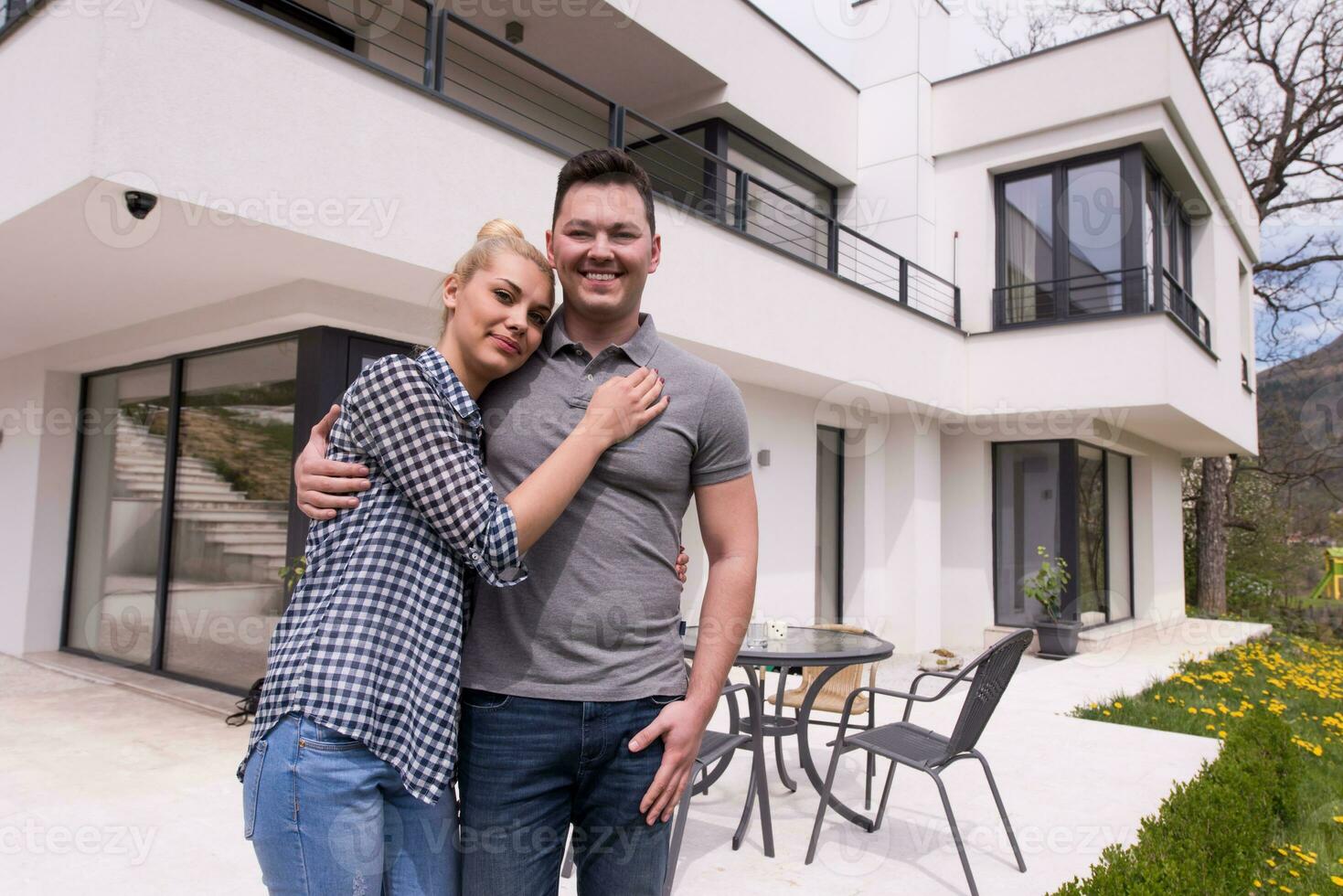 couple hugging in front of  new luxury home photo