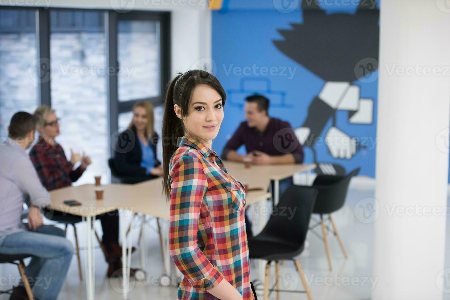 portrait of young business woman at office with team in background photo