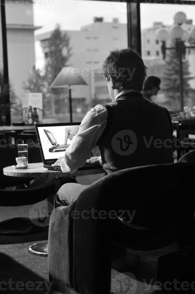 hombre feliz sentado y trabajando en la computadora portátil foto