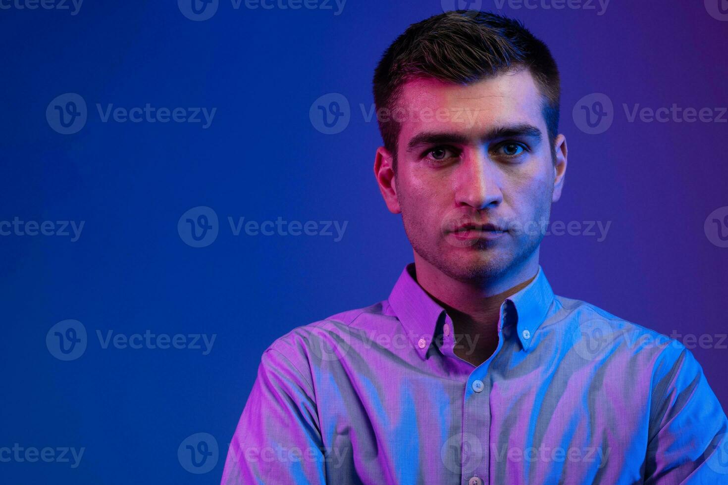 A man in a shirt poses on a dark multicolored neon background photo