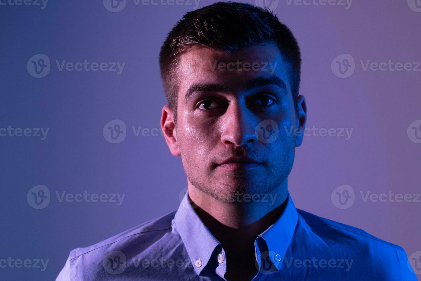 A man in a shirt poses on a dark multicolored neon background photo