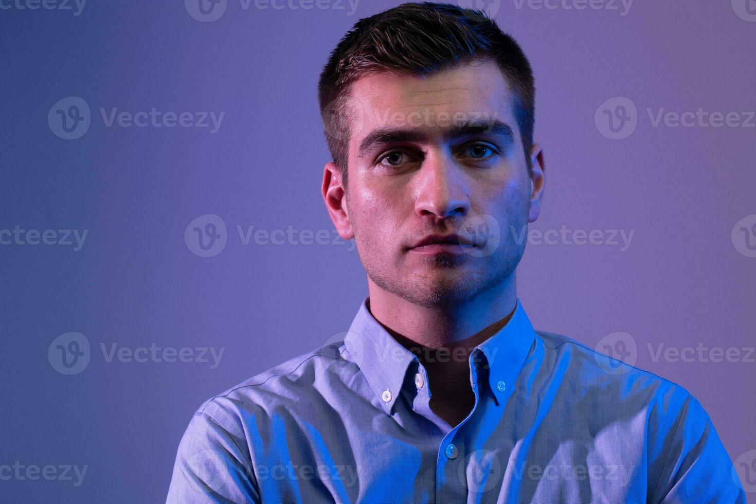 A man in a shirt poses on a dark multicolored neon background photo