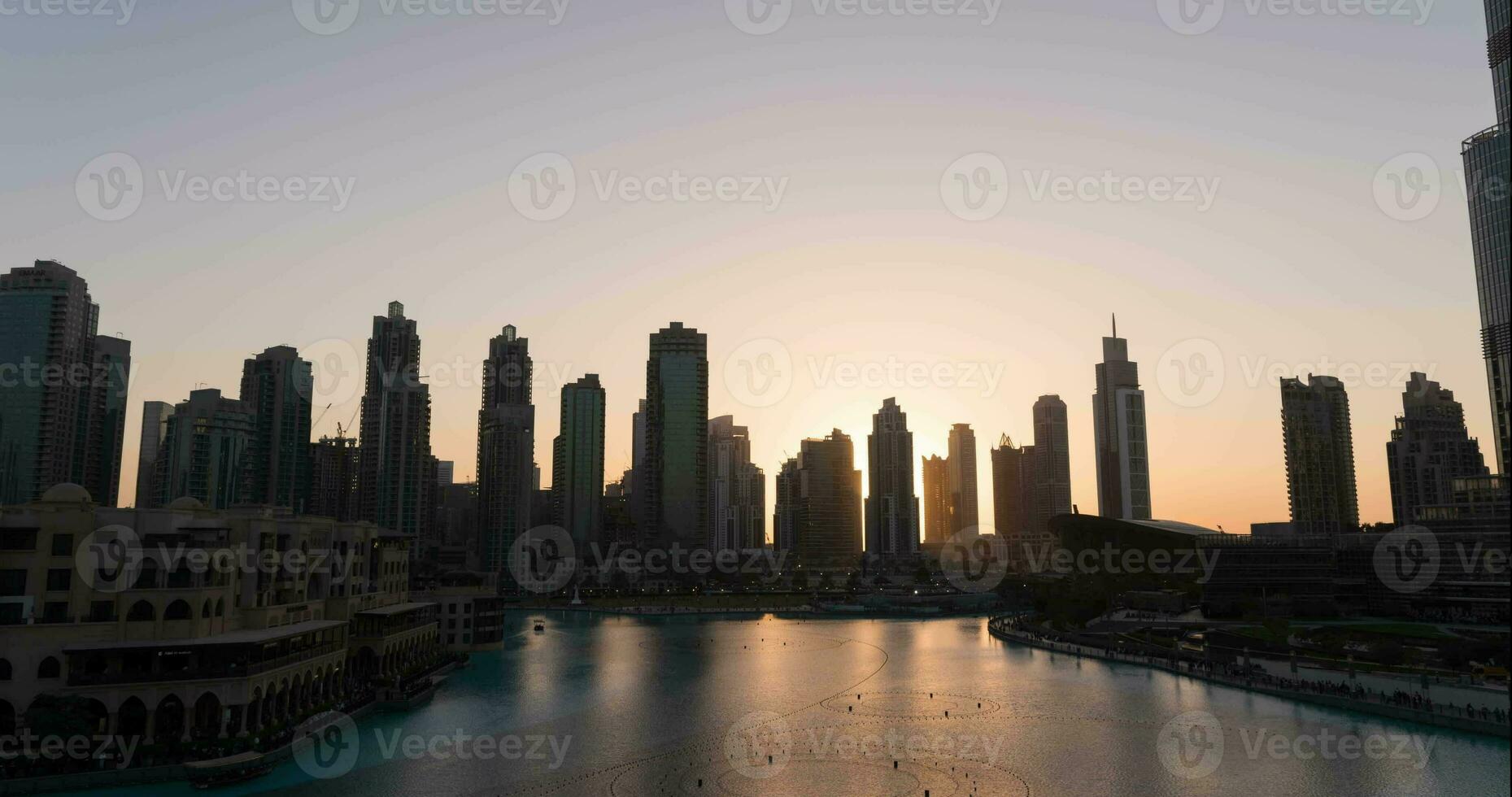 Dubai singing fountains at night view between skyscrapers. Timelapse of city skyline in dusk modern architecture and tall business and residental buildings in UAE capital. photo