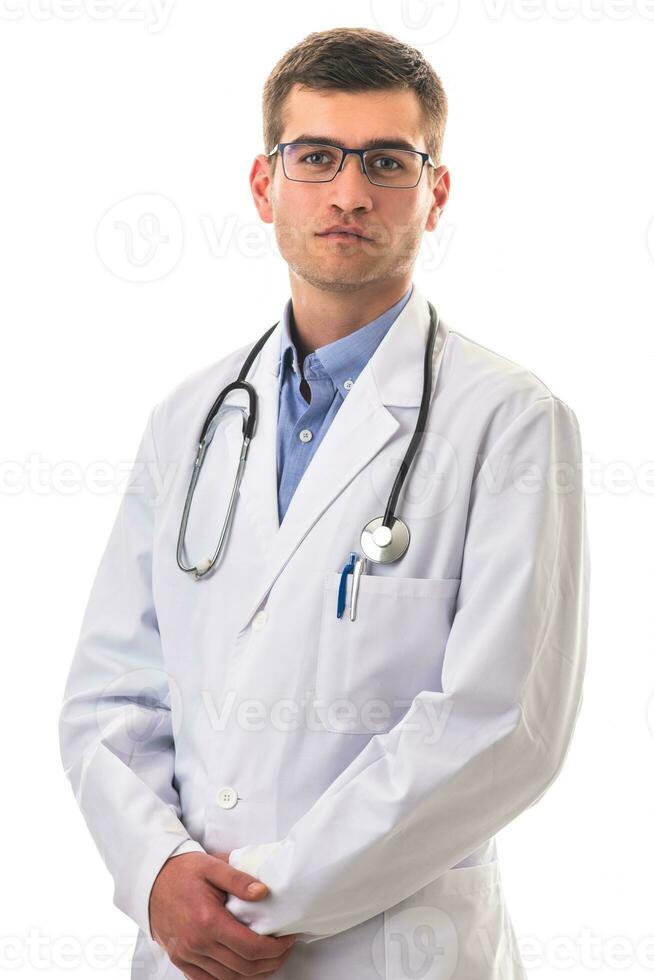 retrato de héroe en blanco abrigo. alegre sonriente joven médico con estetoscopio en médico hospital en pie en contra blanco antecedentes. coronavirus covid-19 peligro alerta foto