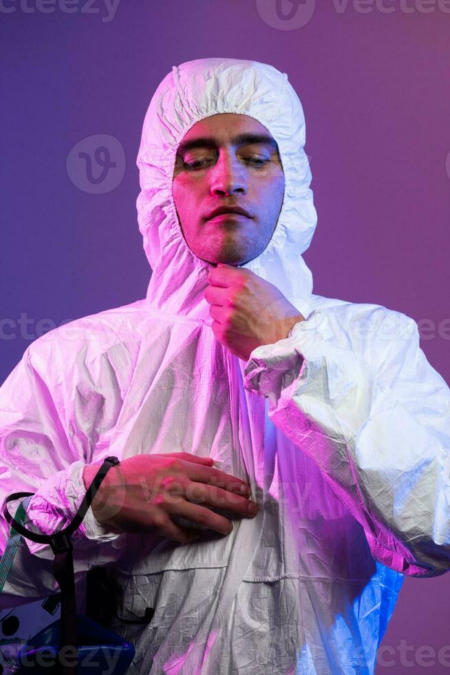 Coronavirus covid-19 pandemic. Doctor scientist wearing protective biological suit and mask due to global healthcare epidemic warning and danger background in blue and pink neon lights background. photo