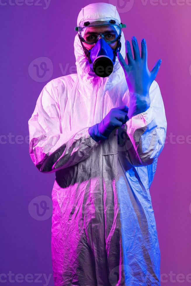 Coronavirus covid-19 pandemic. Doctor scientist wearing protective biological suit and mask due to global healthcare epidemic warning and danger background in blue and pink neon lights background. photo