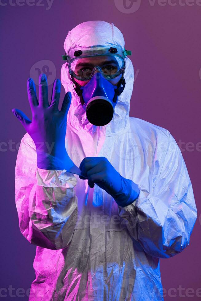 Coronavirus covid-19 pandemic. Doctor scientist wearing protective biological suit and mask due to global healthcare epidemic warning and danger background in blue and pink neon lights background. photo