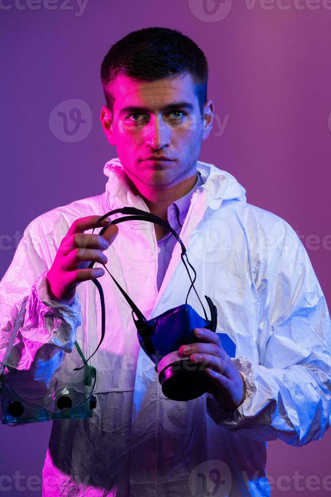 Coronavirus covid-19 pandemic. Doctor scientist wearing protective biological suit and mask due to global healthcare epidemic warning and danger background in blue and pink neon lights background. photo