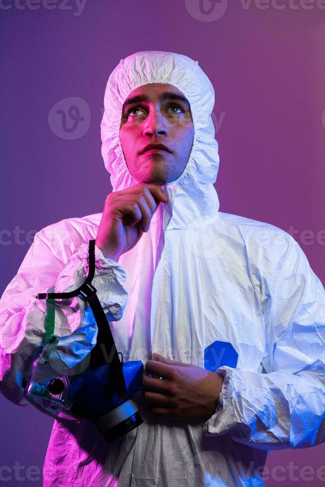 Coronavirus covid-19 pandemic. Doctor scientist wearing protective biological suit and mask due to global healthcare epidemic warning and danger background in blue and pink neon lights background. photo