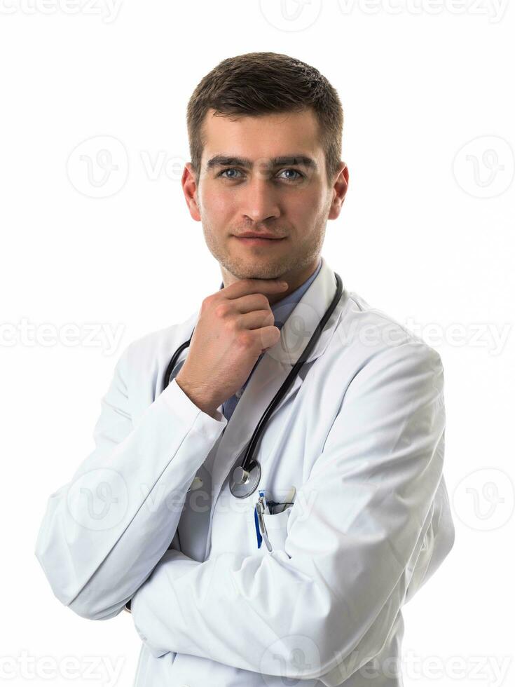 Portrait of hero in white coat. Cheerful smiling young doctor with stethoscope in medical hospital standing against white background. Coronavirus covid-19 danger alert photo
