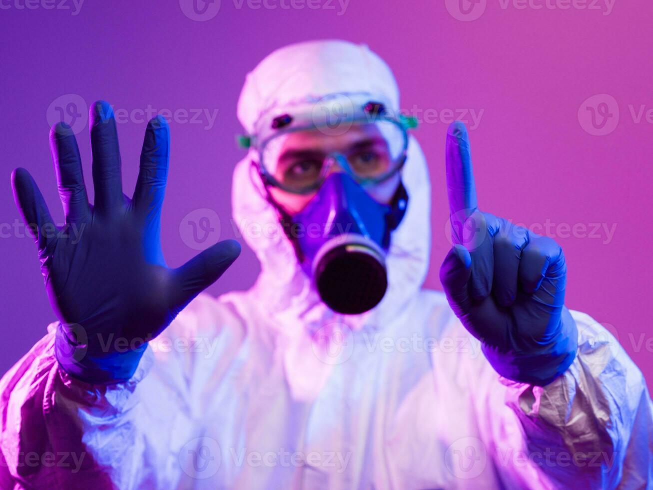 Coronavirus covid-19 pandemic. Doctor scientist wearing protective biological suit and mask due to global healthcare epidemic warning and danger background in blue and pink neon lights background. photo