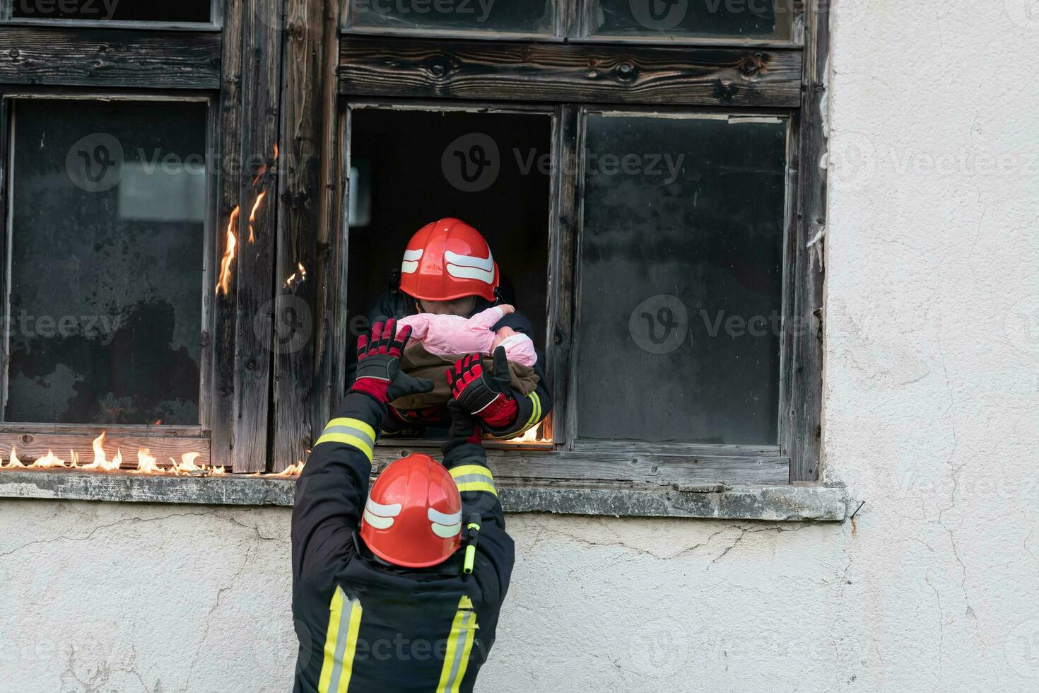 Firefighter hero carrying baby girl out from burning building area from fire incident. Rescue people from dangerous place photo