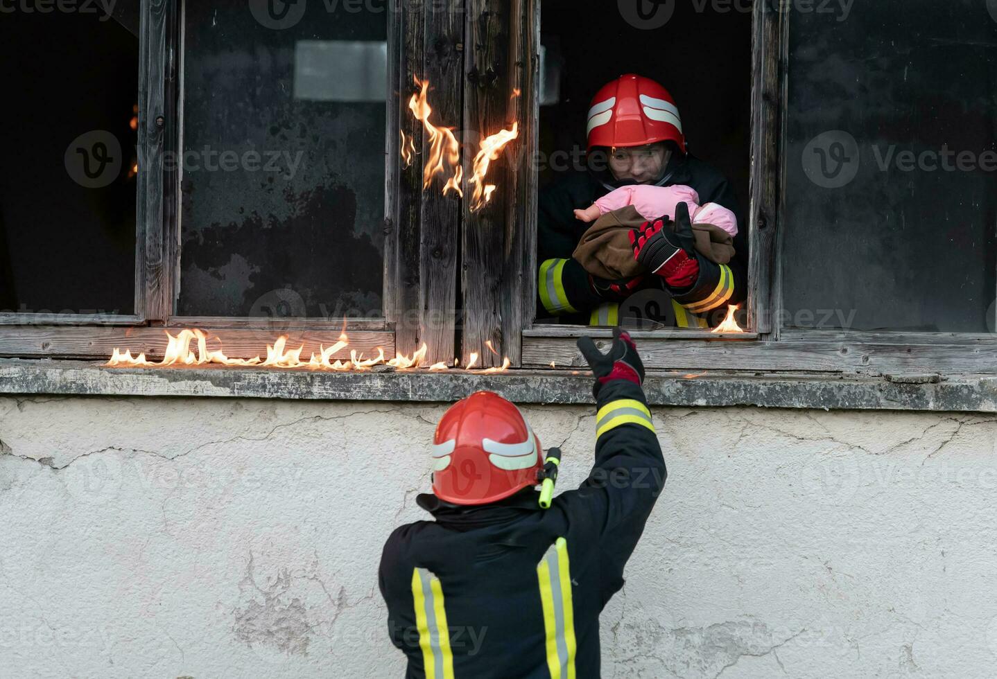 Firefighter hero carrying baby girl out from burning building area from fire incident. Rescue people from dangerous place photo