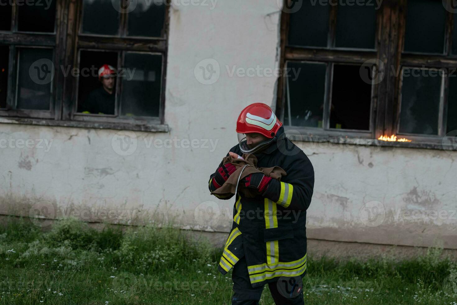 Firefighter hero carrying baby girl out from burning building area from fire incident. Rescue people from dangerous place photo