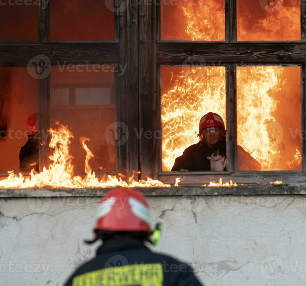 Firefighter hero carrying baby girl out from burning building area from fire incident. Rescue people from dangerous place photo