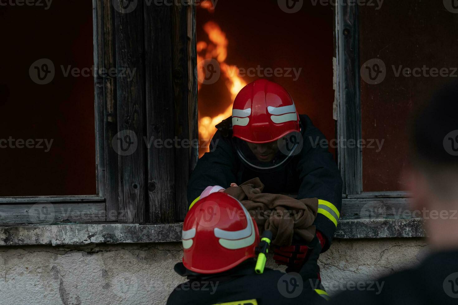 Firefighter hero carrying baby girl out from burning building area from fire incident. Rescue people from dangerous place photo