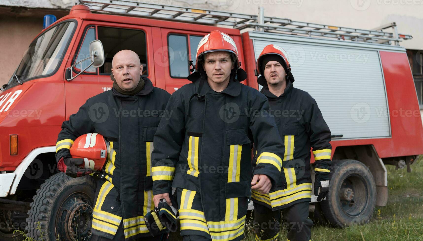 Group of fire fighters standing confident after a well done rescue operation. Firemen ready for emergency service. photo