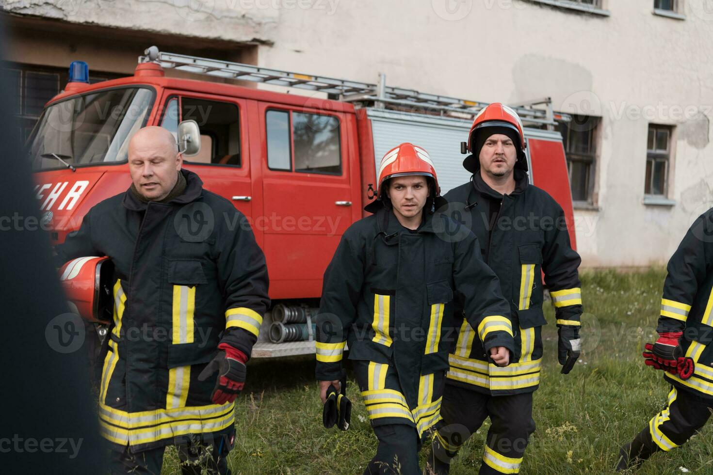 Group of fire fighters standing confident after a well done rescue operation. Firemen ready for emergency service. photo