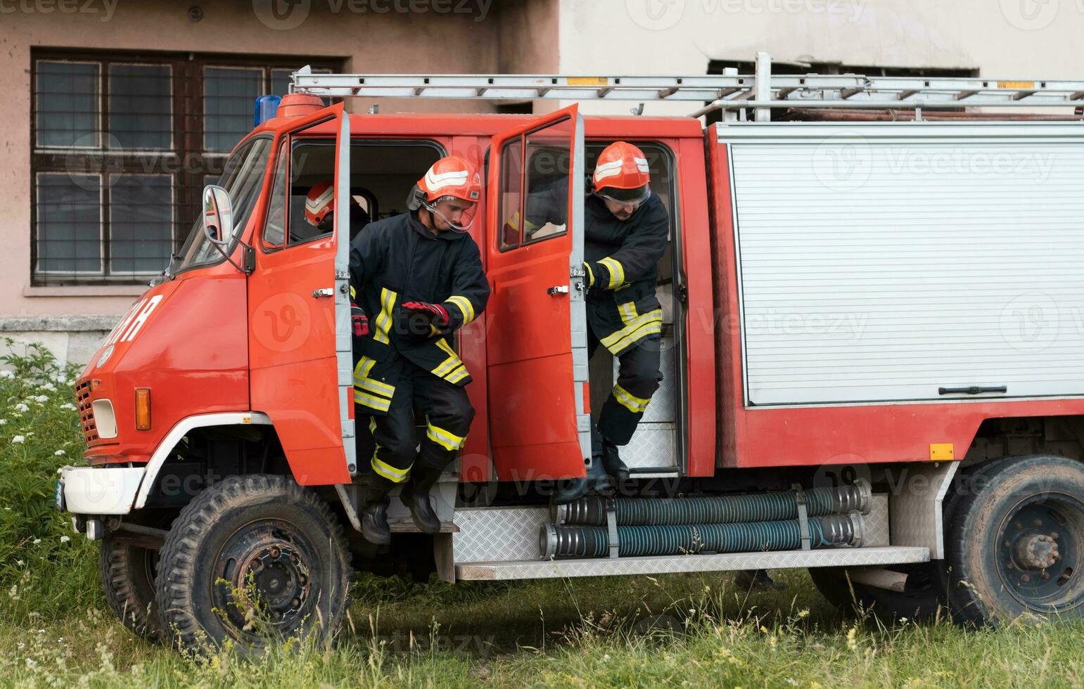 Group of fire fighters standing confident after a well done rescue operation. Firemen ready for emergency service. photo