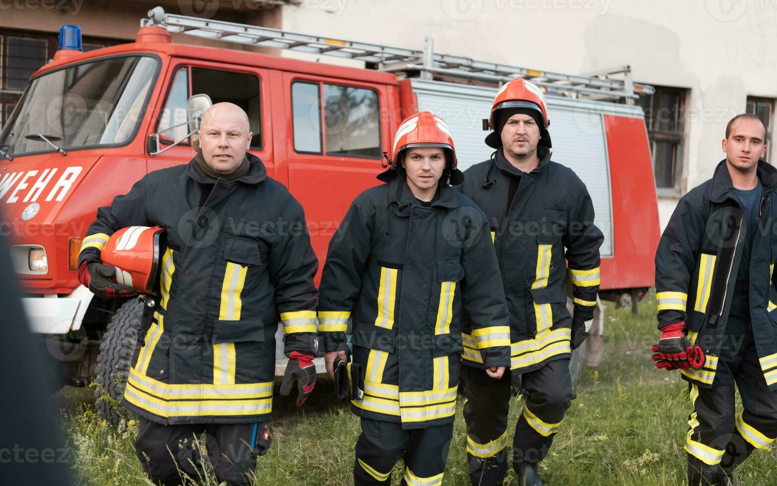 Group of fire fighters standing confident after a well done rescue operation. Firemen ready for emergency service. photo